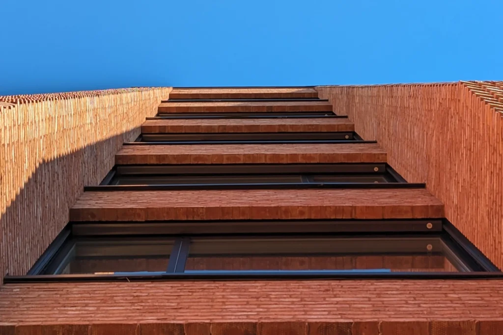 Building exterior with blue sky and sunlight, looking up at building, photograph of Domus Juridica in Oslo by Tobias Rade Evensen. 